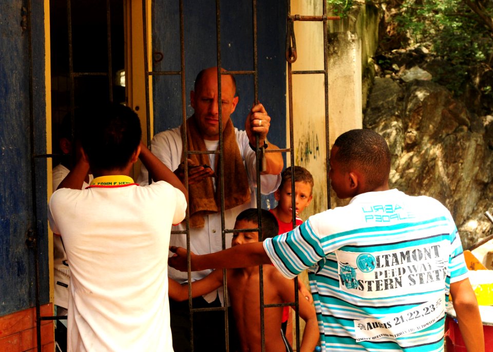 US Navy 100821-N-9301W-657 Cmdr. Scott Smith removes old paint from a doorway gate with the help of local children during a joint community relations project with the Colombian national navy