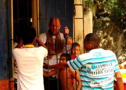 US Navy 100821-N-9301W-657 Cmdr. Scott Smith removes old paint from a doorway gate with the help of local children during a joint community relations project with the Colombian national navy