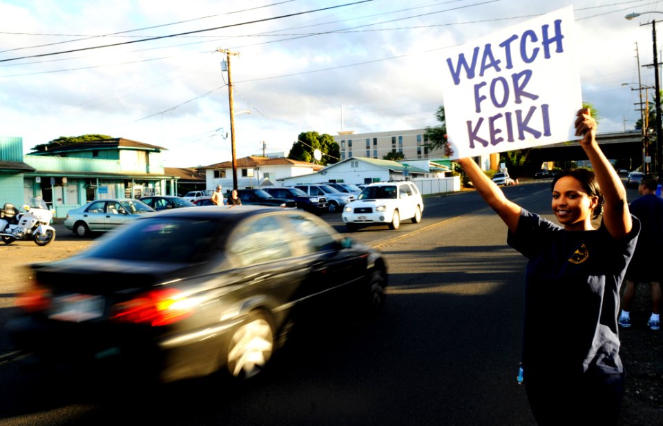 US Navy 100824-N-7498L-075 Ship's Serviceman 1st Class Telehia Sutherland holds a watch for keiki sign along Lehua Avenue in Pearl Harbor, Hawaii, to raise awareness about driving safely and reducing speed in a school zone