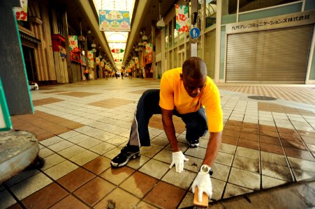 US Navy 100827-N-8335D-037 Legalman 2nd Class Alain Bois, assigned to Fleet Activities Sasebo, cleans the city's main shopping arcade during a community service project