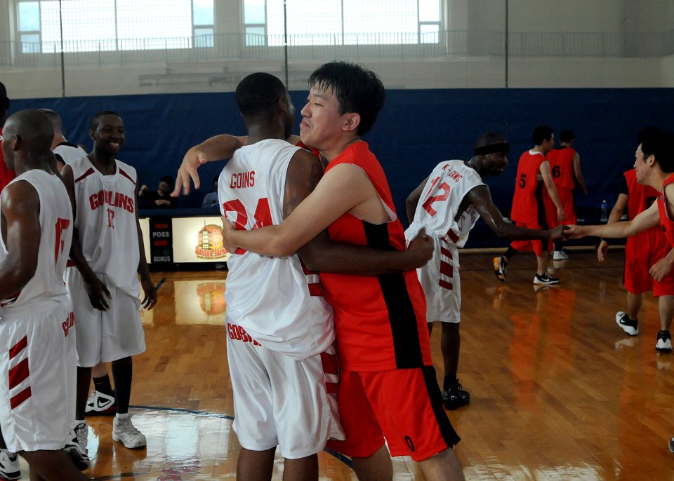 US Navy 100825-N-5215E-089 Cryptologic Technician (Technical) 2nd Class Kenneth Booker, assigned to the forward-deployed amphibious assault ship USS Essex (LHD 2), embraces a Japanese player after a basketball game against the