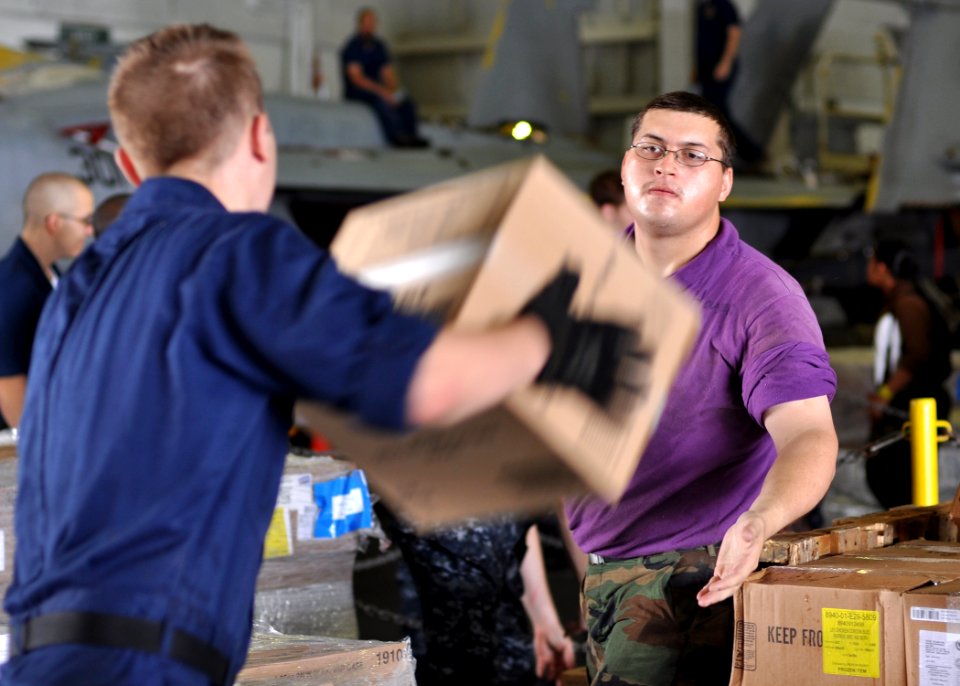 US Navy 100830-N-2013O-103 Aviation Boatswain's Mate (Fueling) Airman Apprentice Ra Houser helps to store boxes of supplies in the hangar bay of USS George Washington (CVN 73)