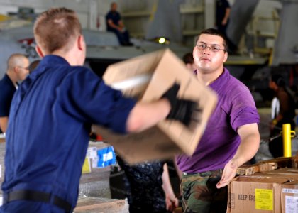 US Navy 100830-N-2013O-103 Aviation Boatswain's Mate (Fueling) Airman Apprentice Ra Houser helps to store boxes of supplies in the hangar bay of USS George Washington (CVN 73)