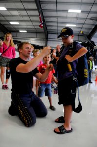 US Navy 100828-N-5366K-103 Special Warfare Operator 1st Class (SEAL) Isaiah Maring, assigned to the U.S. Navy parachute demonstration team, the Leap Frogs, shows a child how to wear his parachute photo