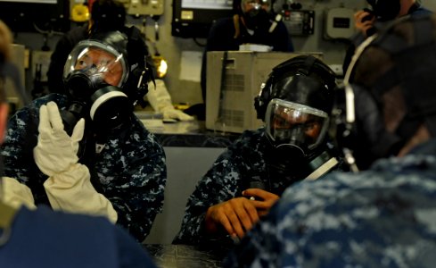US Navy 100830-N-7280V-341 Mass Communication Specialist 2nd Class Steven Khor, left, and Mass Communication Specialist 3rd Class Fidel Hart don MCU-2P gas masks during a chemical, biological and radiological attack drill