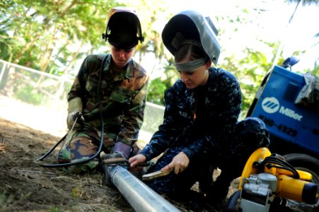 US Navy 100827-N-1531D-159 Steelworker Constructionman Lindzie Bicknell watches as Hull Maintenance Technician 3rd Class Yanina Schiller cleans up welding points from two fused galvanized pipes