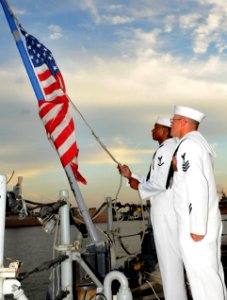 US Navy 100831-N-5812W-002 oatswain's Mate 3rd Class Taylor Branch, left, and Boatswain's Mate 1st Class James Wallen haul down the American flag for the last time during the decommissioning ceremony of the guided-missile friga
