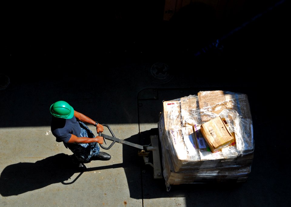 US Navy 100827-N-4044H-115 Hospitalman Richard Harewood pulls a pallet of medical supplies to be sorted aboard HMAS Tobruk (L 50)