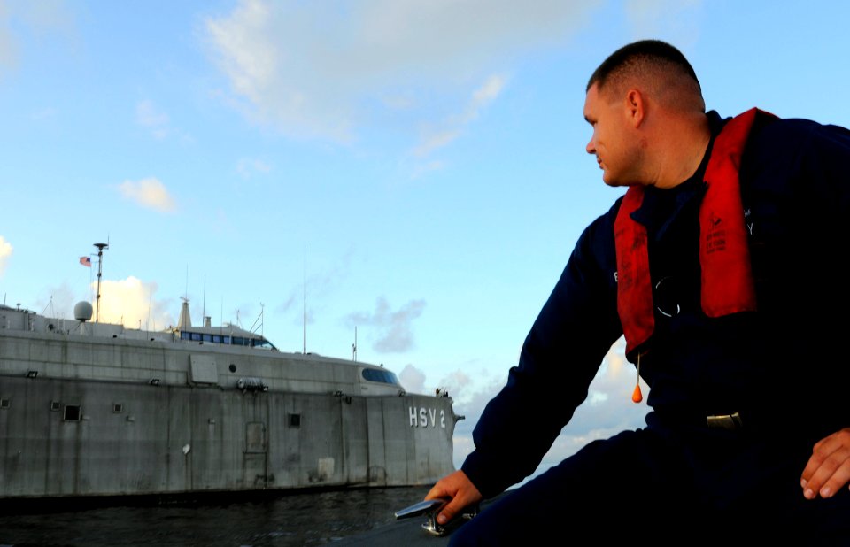 US Navy 100829-N-9643W-331 Damage Controlman 2nd Class Jason Everhart watches High Speed Vessel Swift (HSV 2) from his pilot boat as it cruises off the coast of Guyana enroute to the city of Georgetown