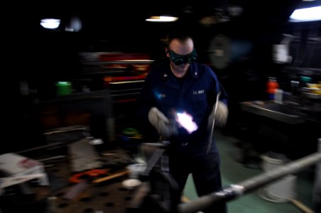 US Navy 100901-N-7293M-086 Navy Hull Technician 2nd Class Daniel Read prepares to silver braze two lengths of pipe together aboard the amphibious transport dock ship USS Ponce (LPD 15)