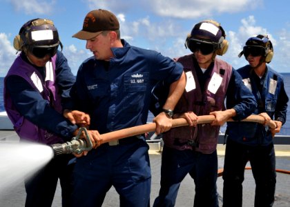 US Navy 100902-N-3620B-062 Aviation Boatswain's Mate (Fuels) 1st Class Jeffrey A. Bennett, center, instructs a hose team during a flight deck fire drill aboard the amphibious transport dock ship USS Denver (LPD 9)
