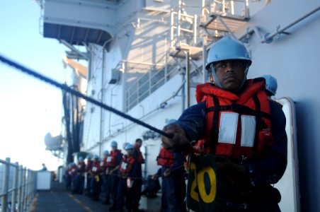 US Navy 100908-N-9950J-744 Ship's Serviceman Seaman Kevin Broom, from Chicago, helps steady the phone and distance line aboard the forward-deployed