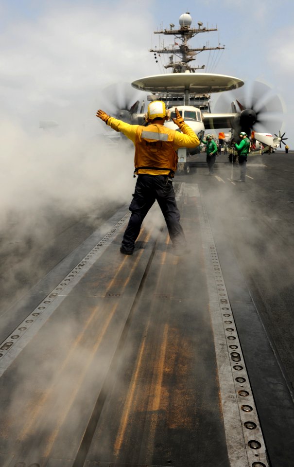 US Navy 100906-N-6362C-013 Steam from a catapult surrounds a flight deck director as he signals an E-2C Hawkeye aboard USS Harry S. Truman (CVN 75)