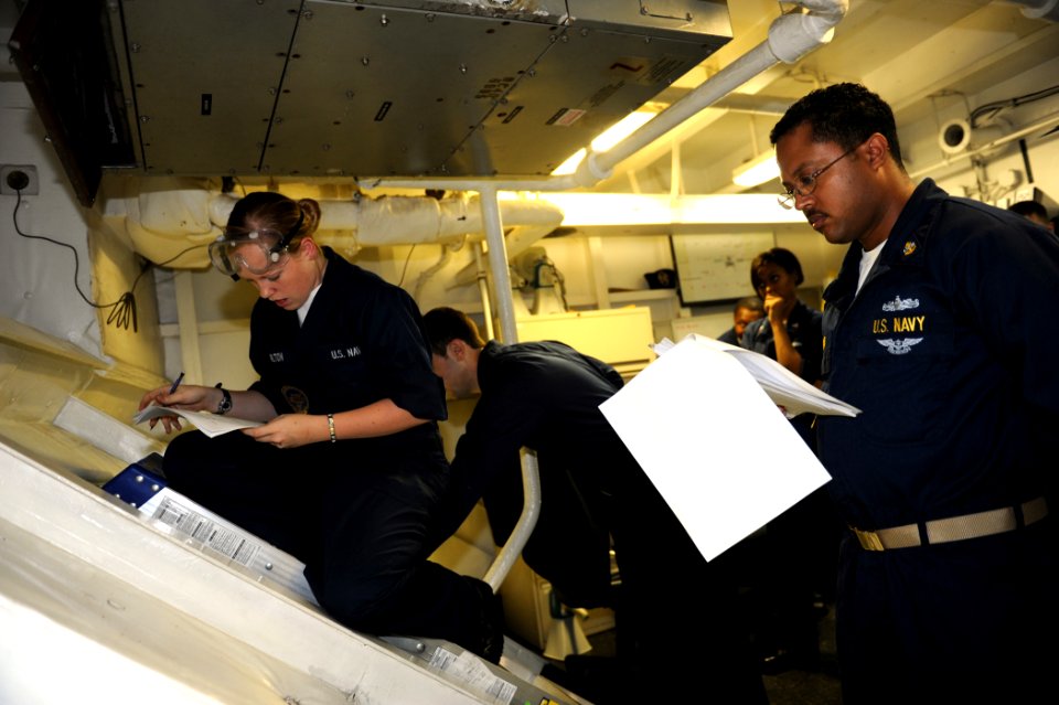 US Navy 100906-N-6362C-091 Seaman Amanda Carlton, left, reviews a maintenance requirement card with Chief Machinist's Mate Thomas Richard aboard US