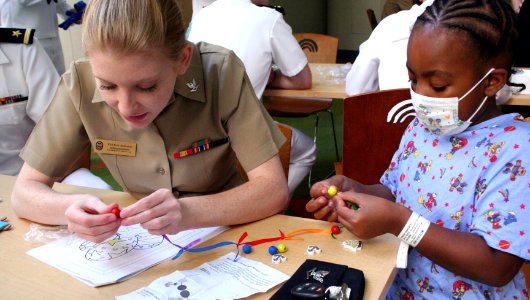 US Navy 100901-N-6220J-045 Yeoman 3rd Class Erin Anderson, assigned to Navy Operational Support Center, Akron, helps a patient at the Rainbow Babies ^ Children's Hospital assemble a necklace