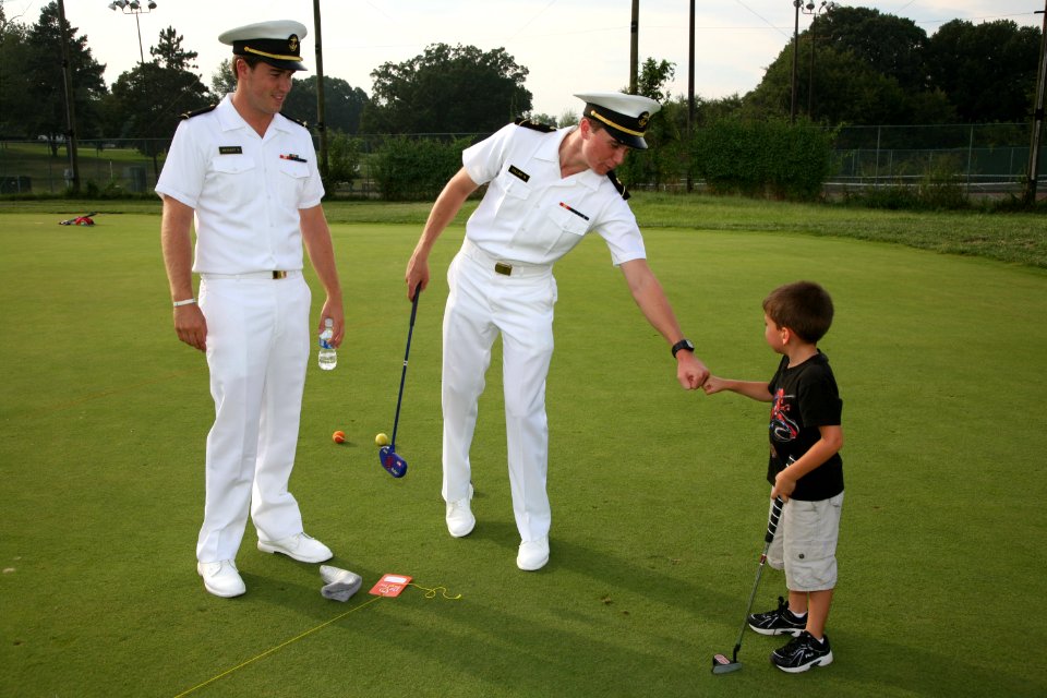 US Navy 100903-N-3271W-159 BALTIMORE (Sept. 3, 2010) Midshipman 3rd Class Pat Collins fist bump with a First Tee participant as Midshipman Ensign Robert Merkert looks on