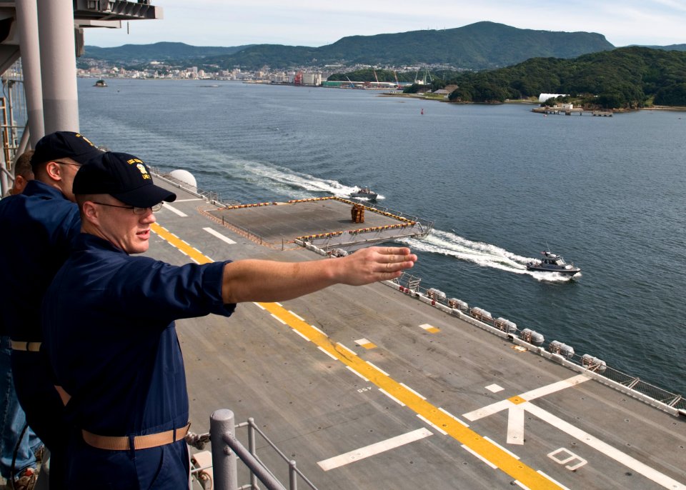 US Navy 100901-N-9950J-281 Lt. j.g. Peter Rusch points to a ship in Sasebo Harbor as the forward-deployed amphibious assault ship USS Essex (LHD 2) gets underway for an annual fall patrol