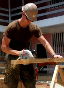 US Navy 100902-N-4971L-011 A Seabee assigned to Naval Mobile Construction Battalion (NMCB) 7 embarked aboard High Speed Vessel Swift (HSV 2), cuts boards to build an additional classroom at Plaisance Community High School