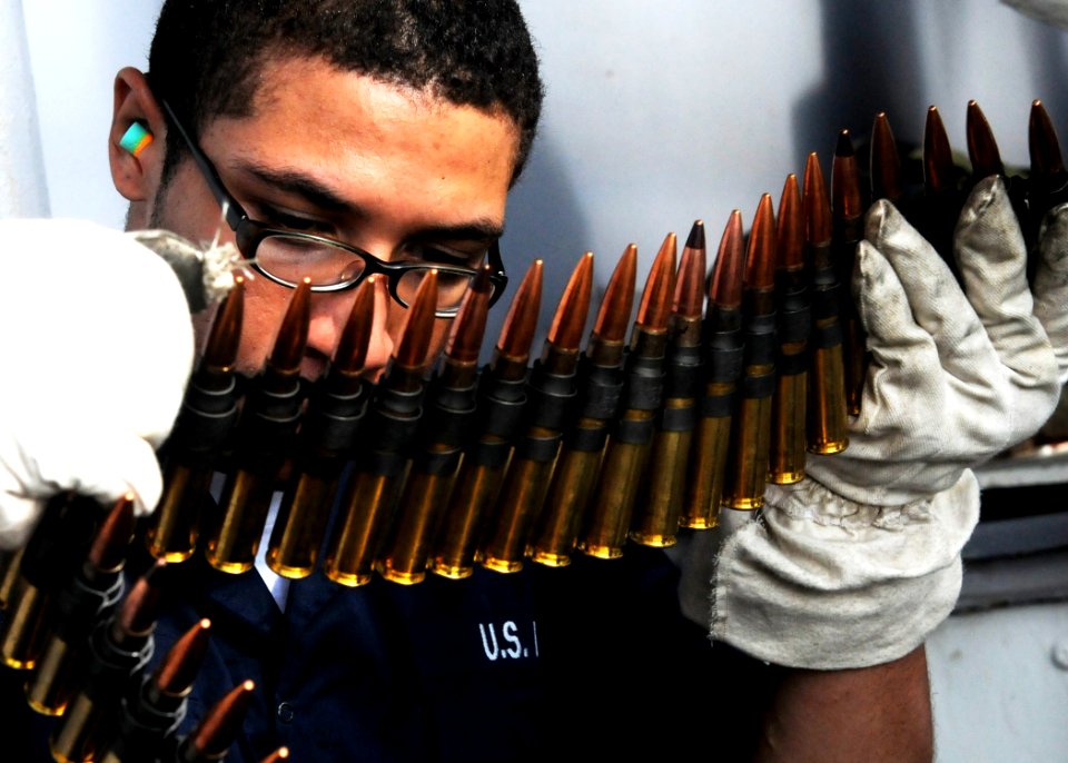 US Navy 100902-N-5538K-101 Aviation Ordnanceman Seaman Kenneth R. Mack, assigned to the forward-deployed amphibious assault ship USS Essex (LHD 2), breaks .50-caliber ammunition chains into 20-round lengths