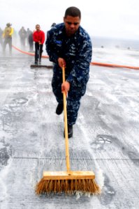 US Navy 100902-N-7488A-874 Chief (Sel.) Aviation Boatswain's Mate (Handling) Shaven Savoy scrubs the flight deck during a scrubbing exercise aboard USS Carl Vinson (CVN 70)