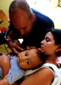 US Navy 100907-N-1531D-169 Lt. Cmdr. Jason Higginson, from Los Angeles, checks the ear of an infant during a Continuing Promise 2010 medical civic photo