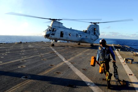 US Navy 100908-N-8335D-371 Ship's Serviceman Seaman Joseph Davis runs for safety after removing a chock and chain from a CH-46 Sea Knight helicopte