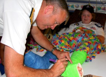 US Navy 100914-N-3038C-016 Rear Adm. William D. French autographs a patient's cast at Shriner's Hospital during a Caps For Kids event during Salt L