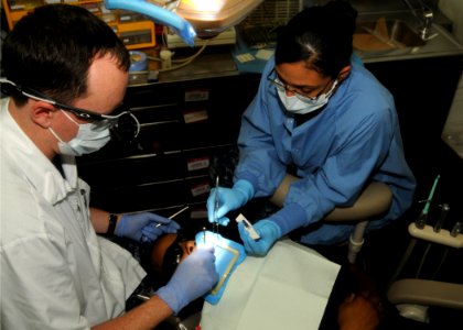 US Navy 100909-N-9643S-040 Lt. Travis Rust and assistant Hospitalman Anjuli Fine perform oral surgery on a Sailor aboard the aircraft carrier USS G