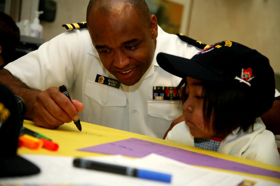 US Navy 100909-N-3271W-055 Lt. Bashon Mann, assigned to the Navy Office of Community Outreach, draws with a patient during a Caps for Kids event