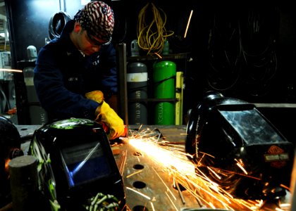 US Navy 100915-N-6427M-056 Hull Maintenance Technician 3rd Class Dustin Green removes weld splatters and other residue from the welding table in th