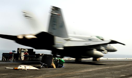 US Navy 100918-N-6362C-005 A catapult operator takes cover as an F-A-18C Hornet assigned to the Ragin' Bulls of Strike Fighter Squadron (VFA) 37 la