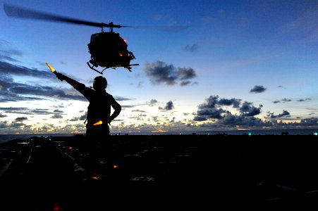 US Navy 100914-N-8335D-154 Boatswain's Mate 3rd Class Lanh Dinh directs a UH-IN Huey helicopter during take off from the amphibious dock landing sh