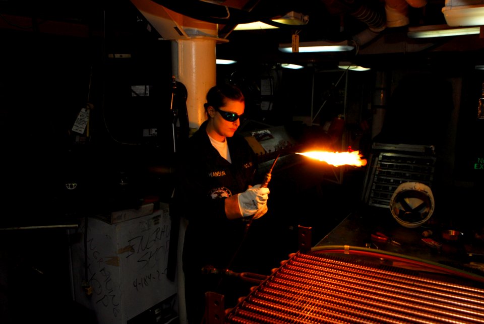 US Navy 101018-N-5031T-087 Hull Maintenance Technician fireman Christina Swanson, from Minneapolis, Minn., brazes on a new fitting on a radiator in