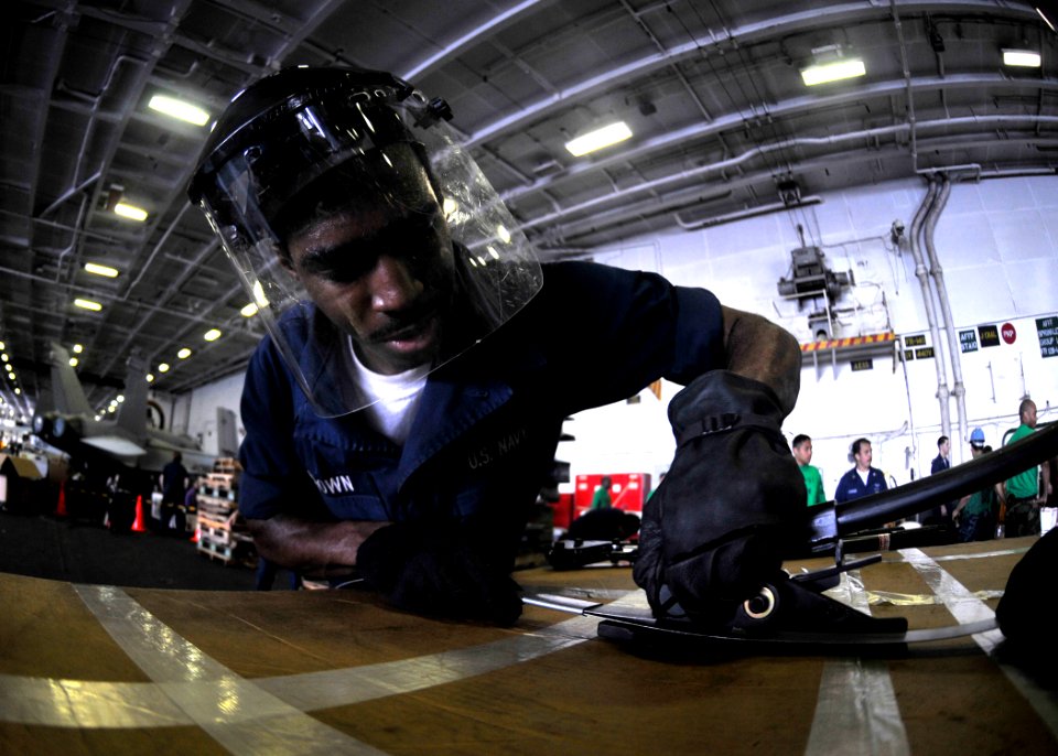 US Navy 101014-N-7103C-122 Logistics Specialist Seaman Kenneth Brown, from Beaufort, S.C., bands a box of cargo to a pallet in the hangar bay aboar