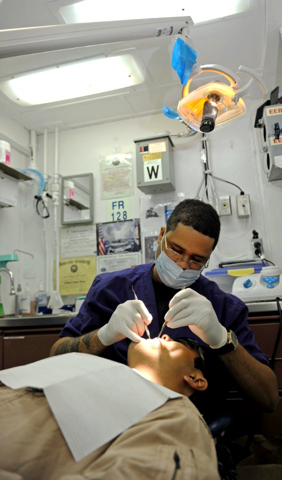 US Navy 101016-N-6362C-027 Hospital Corpsman 3rd Class Anthony Miller performs a routine teeth cleaning in the dental department aboard the aircraf