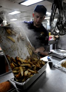 US Navy 101018-N-5016P-005 Culinary Specialist Seaman Mike Driscoll prepares breakfast aboard the guided-missile cruiser USS Cape St. George (CG 71