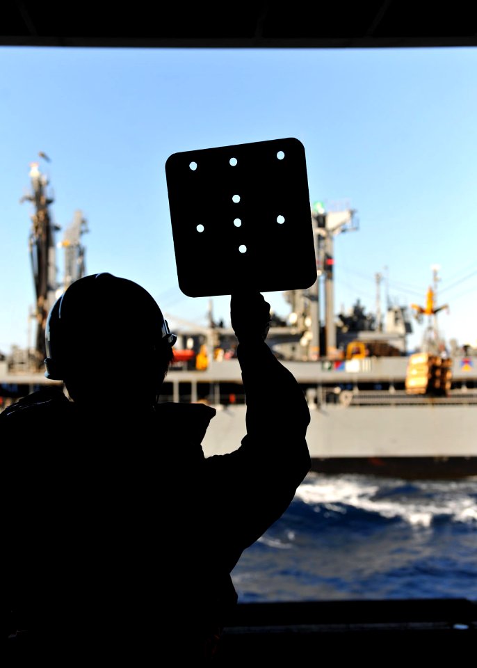 US Navy 101017-N-3374C-221 A Sailor aboard the aircraft carrier USS George H.W. Bush (CVN 77) signals to the Military Sealift Command fleet replen