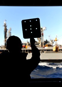 US Navy 101017-N-3374C-221 A Sailor aboard the aircraft carrier USS George H.W. Bush (CVN 77) signals to the Military Sealift Command fleet replen