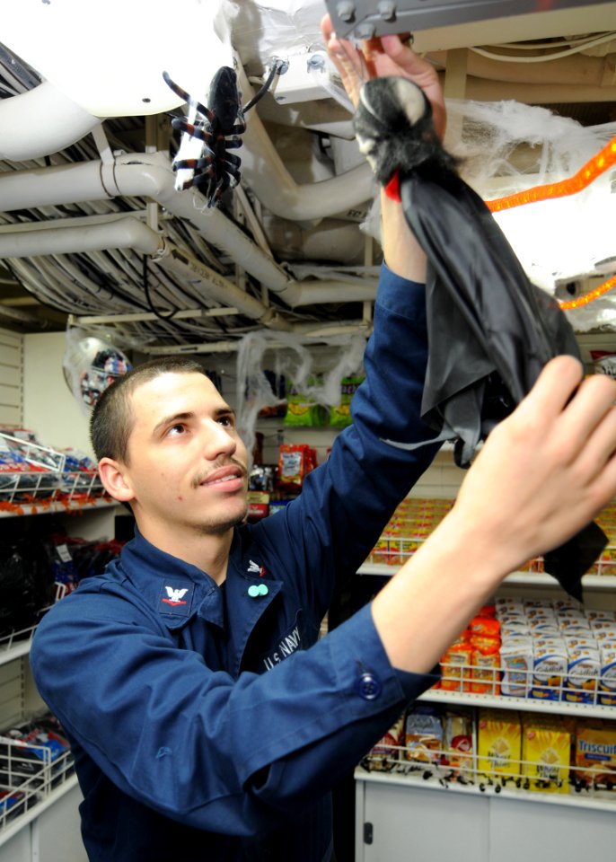 US Navy 101018-N-5016P-237 Ship's Serviceman 3rd Class Charles Mitchell hangs Halloween decorations in the ship's store aboard the guided-missile c