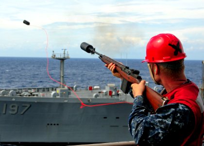 US Navy 101018-N-5538K-071 Aviation Ordnanceman Eric C. Bell fires a shot line from the starboard side of the forward-deployed amphibious assault s