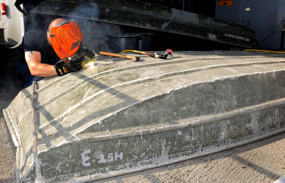 US Navy 101018-N-6362C-056 Hull Maintenance Technician 3rd Class Christopher Pizzino makes a welding repair to an aluminum boat on the fantail aboa