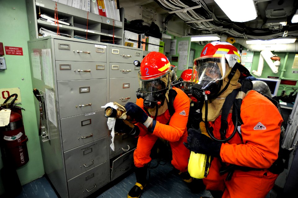 US Navy 101022-N-8335D-030 Sailors wearing firefighting gear enter an office to fight a simulated fire during a general quarters drill aboard the a