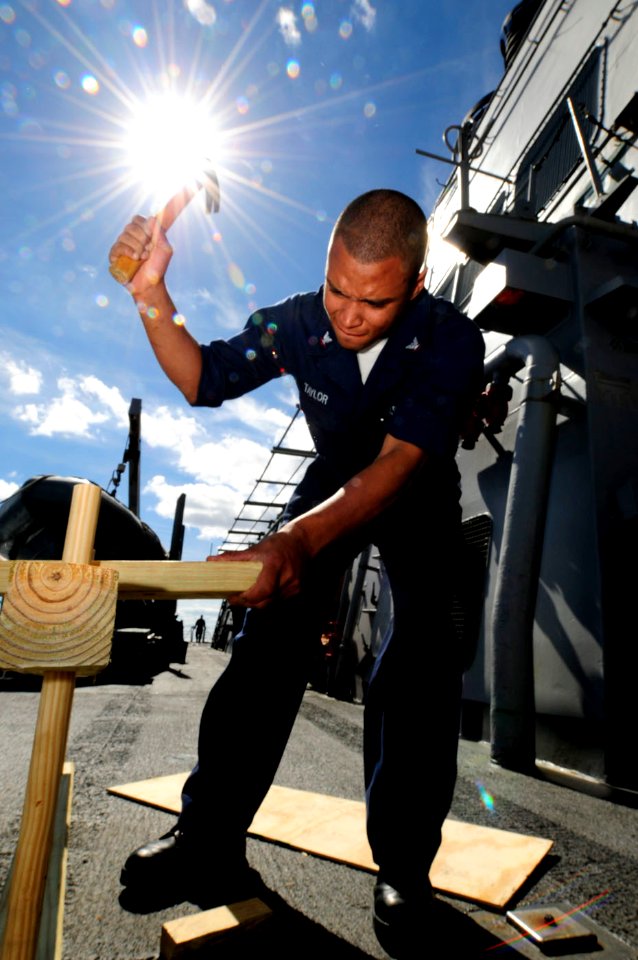 US Navy 101024-N-8913A-096 Gunner's Mate 3rd Class Charles A. Taylor hammers wood in place for shooting targets on the weather deck aboard the guid