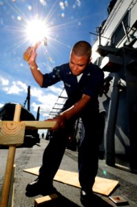 US Navy 101024-N-8913A-096 Gunner's Mate 3rd Class Charles A. Taylor hammers wood in place for shooting targets on the weather deck aboard the guid