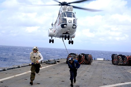 US Navy 101021-N-8335D-371 Service members run for safety after hooking a pole pendant to an SA-330j Puma helicopter during a vertical replenishmen
