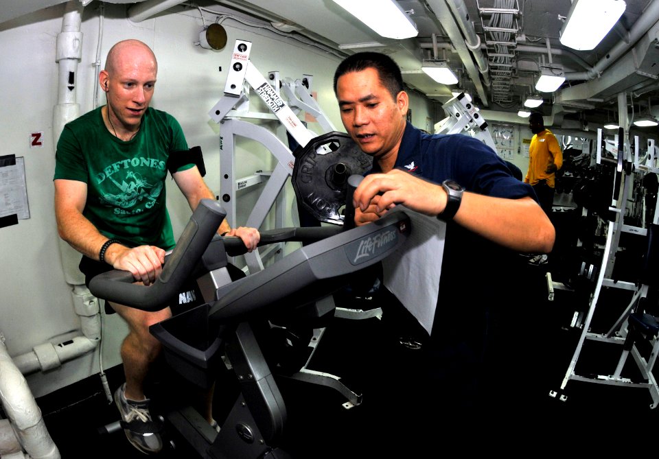 US Navy 101024-N-7103C-079 Lt. j.g. Neal Soladay, left, from Columbia, S.C., finishes his 20-minute cycle on an exercise bicycle during an indoor t
