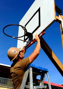 US Navy 101025-N-1531D-392 Utilitiesman 2nd Class Cody Woitena levels a basketball hoop during a Continuing Promise 2010 engineering community serv