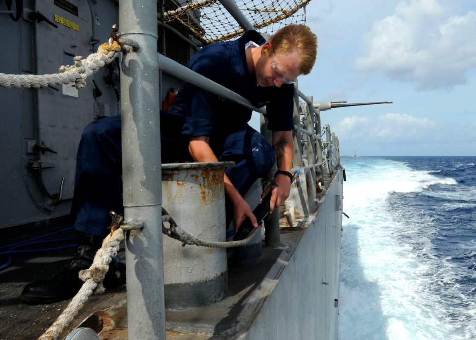 US Navy 101025-N-6632S-128 Seaman Greg J. Anderson, assigned to the deck department, removes paint from bits with a needle gun aboard the guided-mi