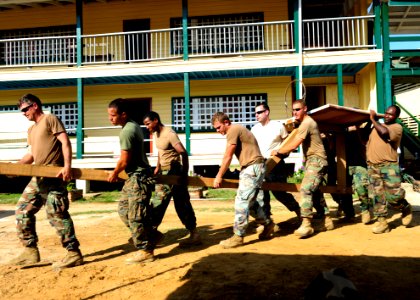 US Navy 101025-N-1531D-306 Sailors and Marines carry a basketball hoop to the court in front of the Corentyne School