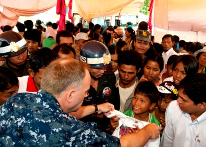 US Navy 101028-N-6770T-055 Lt. Cmdr. Mike Morley, assigned to Commander Task Force 73 in Singapore, hands out donated clothes to local children at
